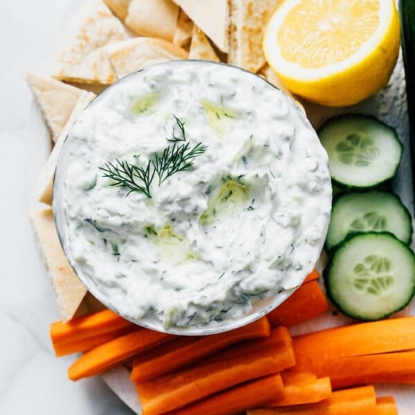 Best tzatziki recipe with pita bread and veggies on a marble table.