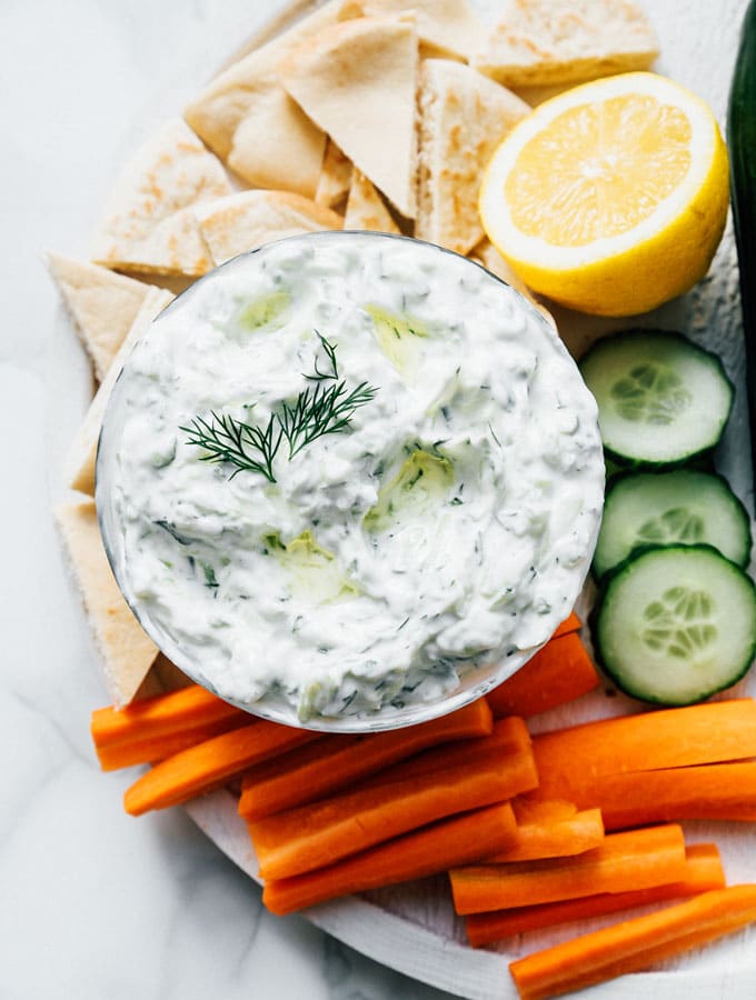 Best tzatziki recipe with pita bread and veggies on a marble table. 