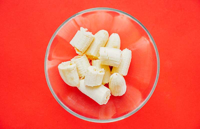 Chunks of bananas in a glass bowl on a red background
