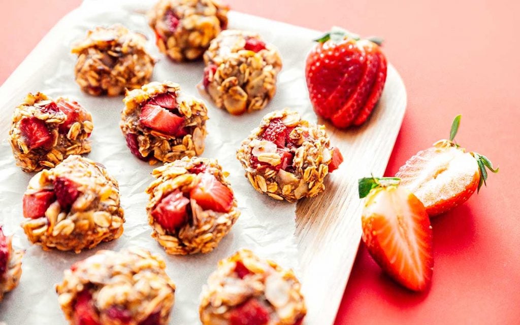 Strawberry oat cookies on a wooden plate with a red background