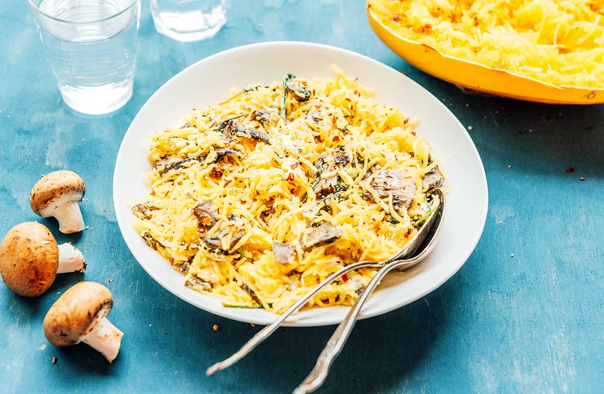 A dish filled with spaghetti squash with mushrooms, spinach, and goat cheese