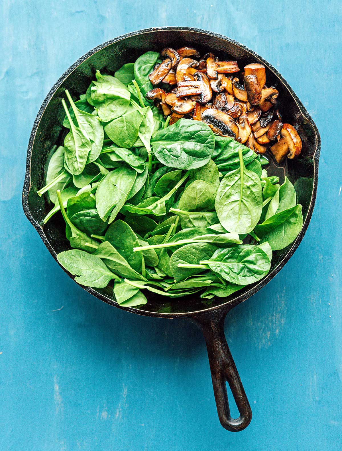 A saute pan filled with mushrooms and spinach