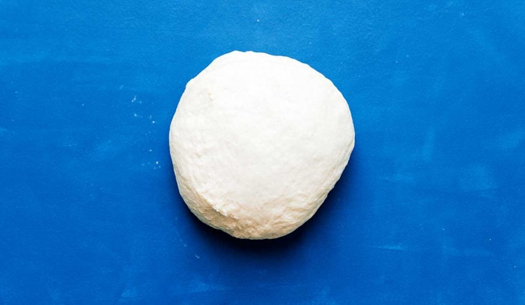 Kneaded ball of dough on a blue background