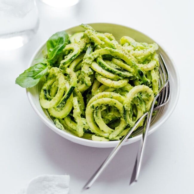 This spiralized zucchini pasta is tossed in creamy basil and avocado pesto to make a deliciously low carb and gluten-free dinner!
