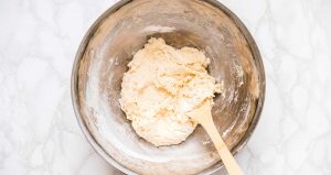 Dough in a metal bowl with a wooden spoon