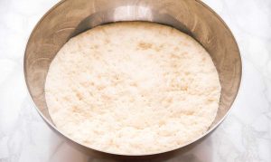 Risen yeast dough in a metal bowl