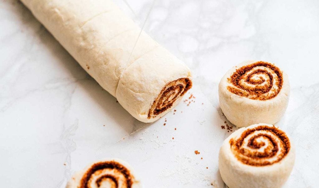 Cutting cinnamon rolls with floss on a marble background