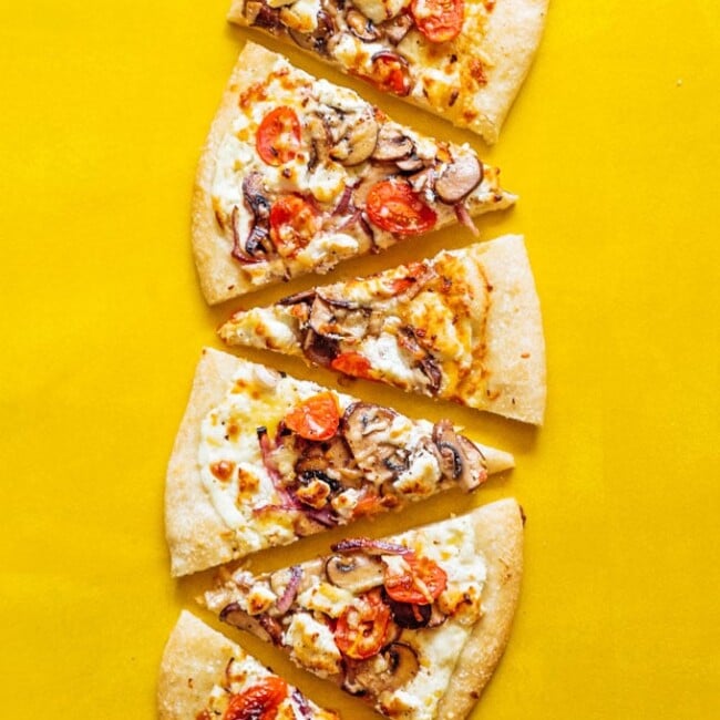 Goat cheese pizza slices on yellow background