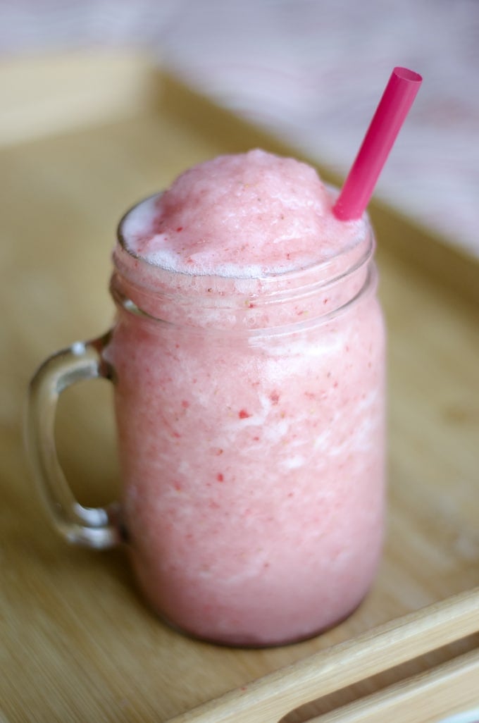 Pink strawberry smoothie in a mason jar with strawberries
