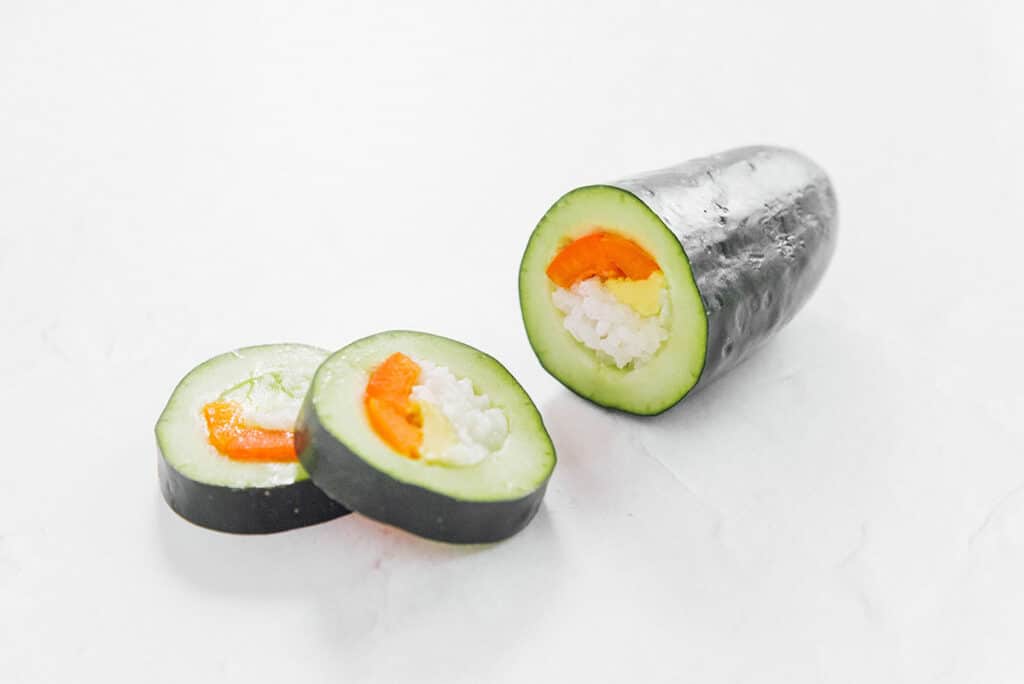 Closeup of stuffed cucumber sushi with rice, carrots, and avocado