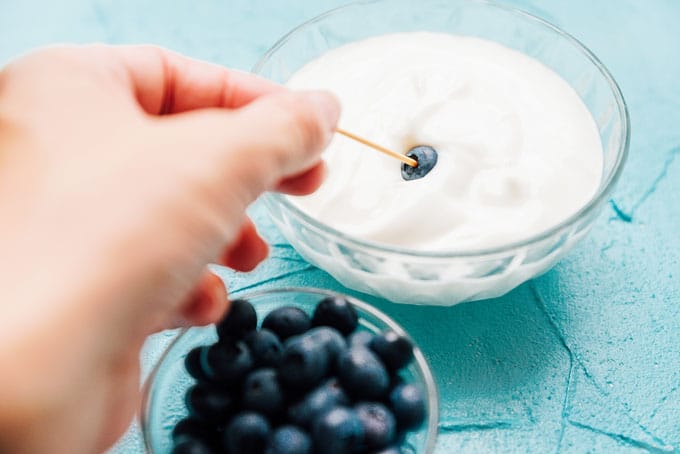 Dipping a blueberry in yogurt with toothpick