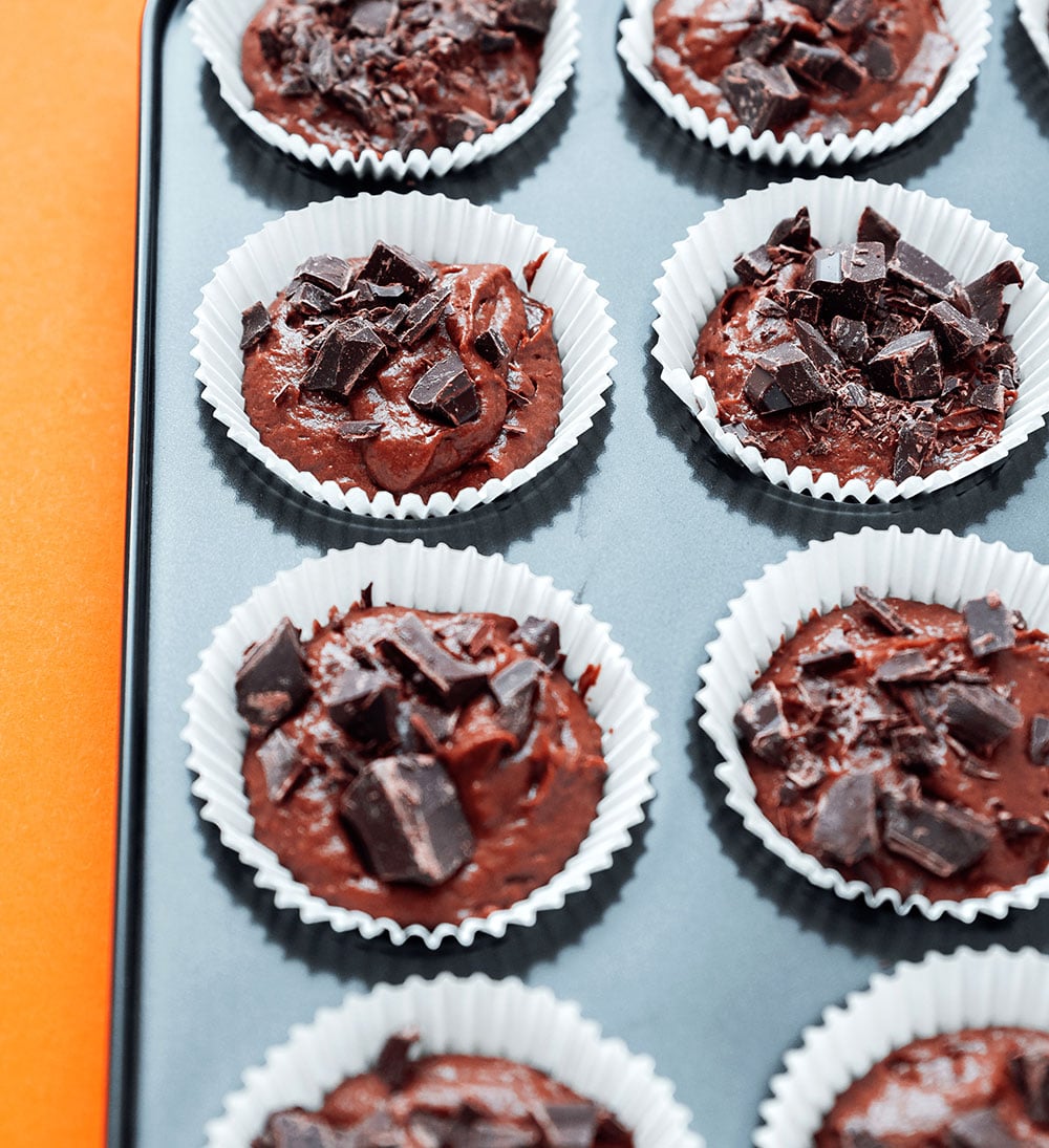 Healthy chocolate cupcakes in a muffin tin on an orange background