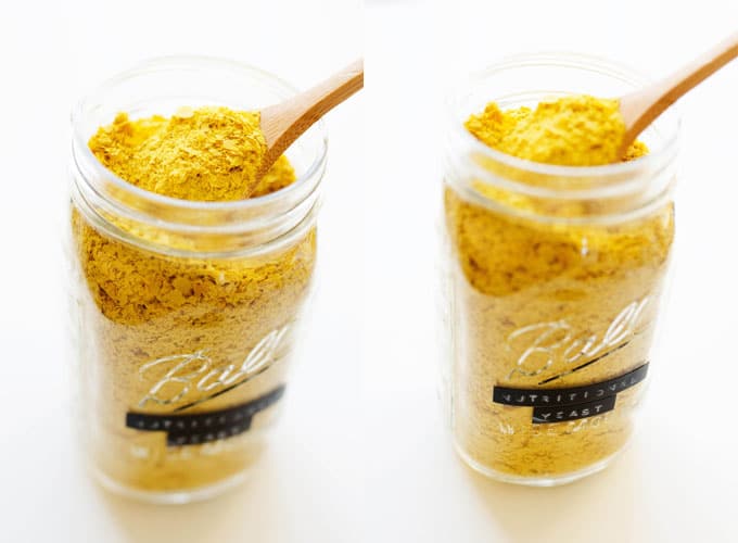 Jar of nutritional yeast on a white background with a spoon in it