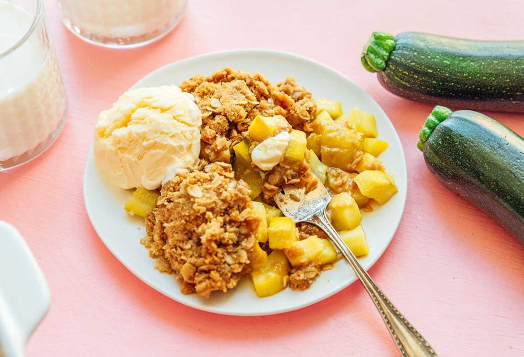 A white plate filled with a heaping portion of zucchini dessert crisp and vanilla ice cream