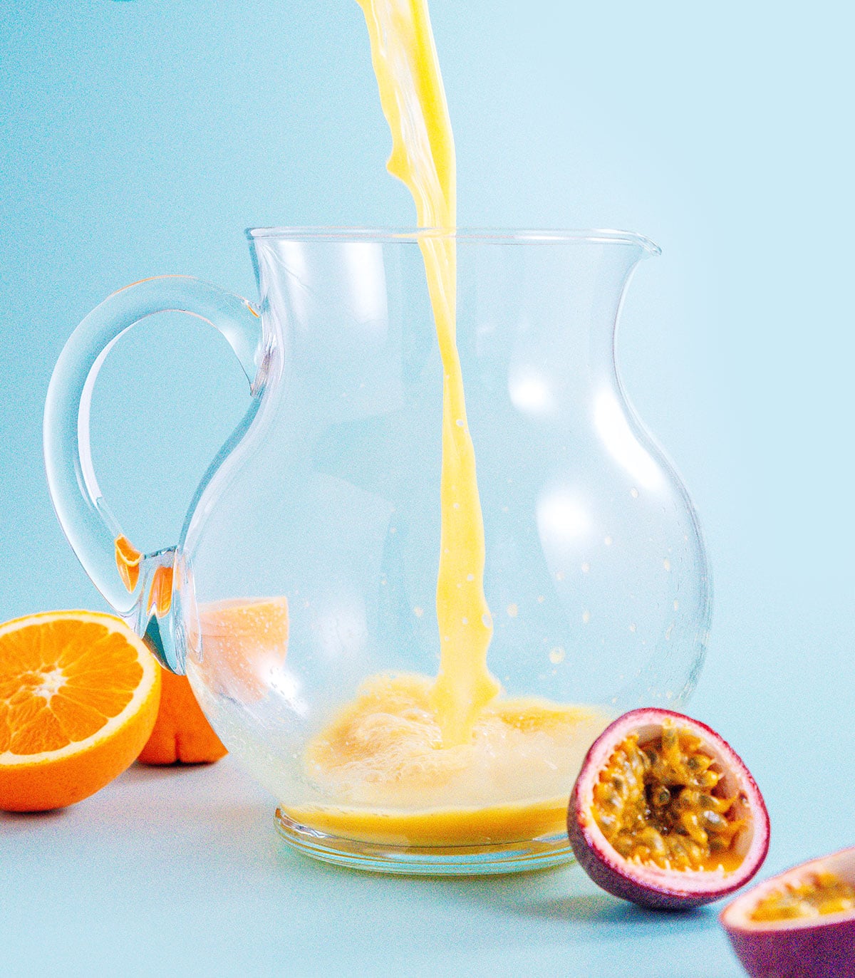 Pouring passion fruit juice into a pitcher with a blue background