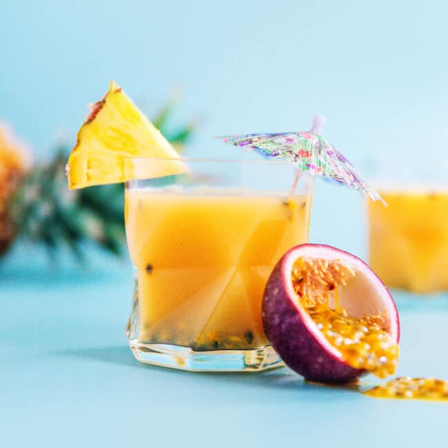 Passion orange guava juice (pog juice) in a glass with a passion fruit on a blue background