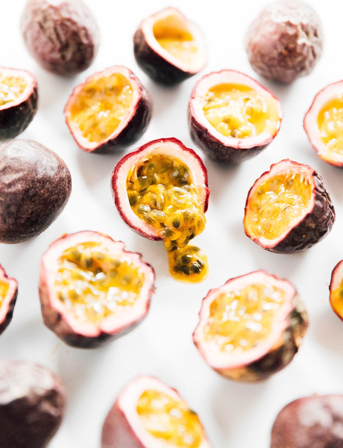 Passion fruit cut in half with the seeds coming out on a white background