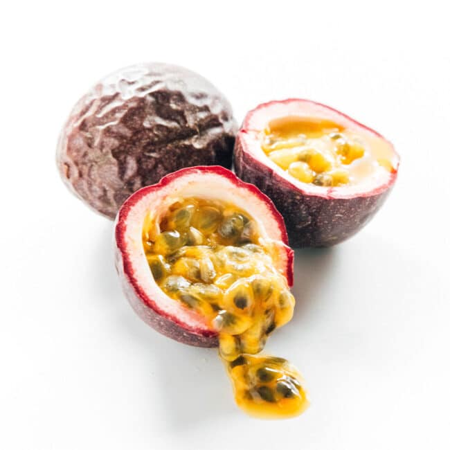 Passion fruit cut in half with the seeds coming out on a white background