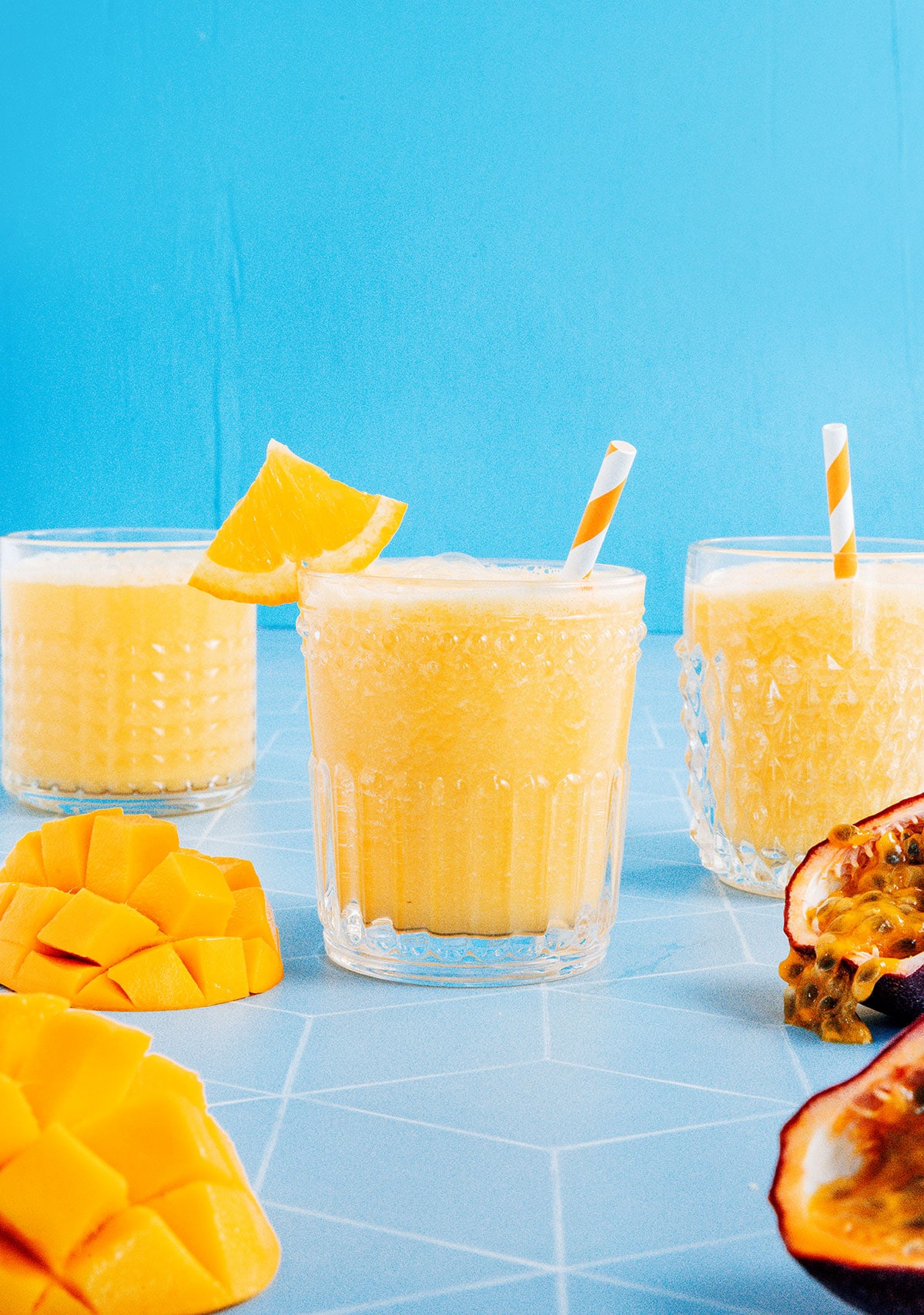 Three glasses of mango juice with a blue background