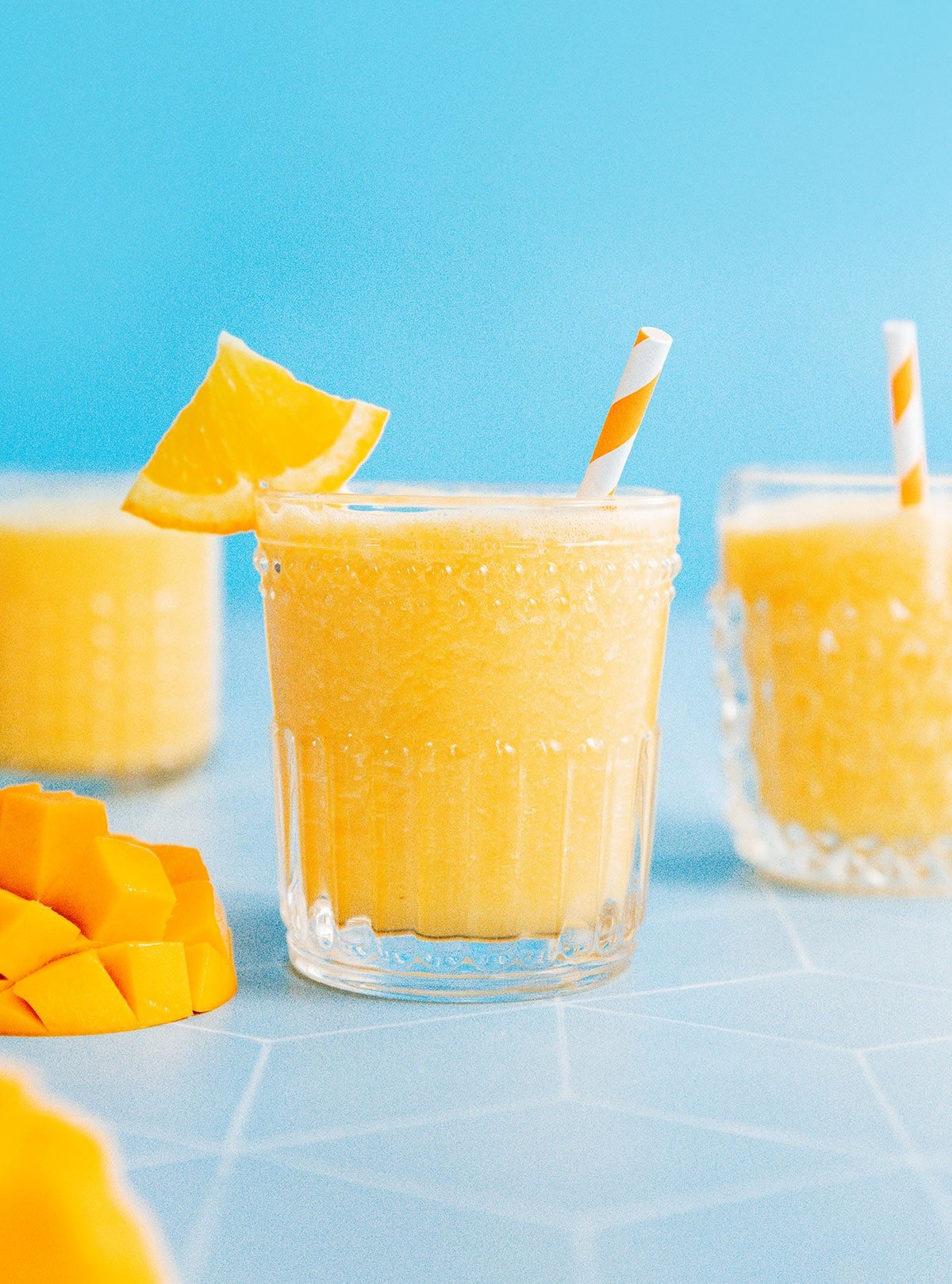 Three glasses of mango juice with a blue background