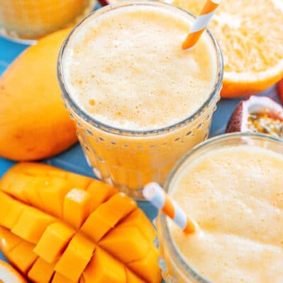Mango juice in a glass surrounded by mangoes