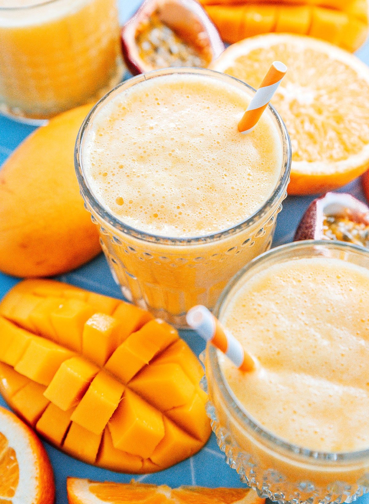 Mango juice in a glass surrounded by mangoes