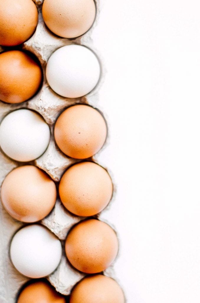 White and brown eggs in a carton on a white background