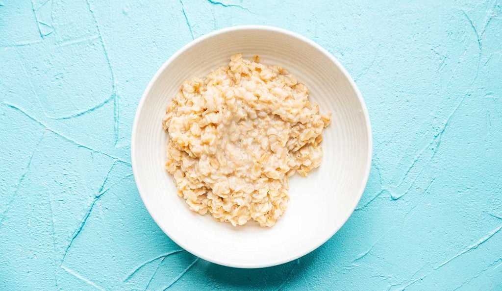 Oatmeal in a white bowl on a blue background