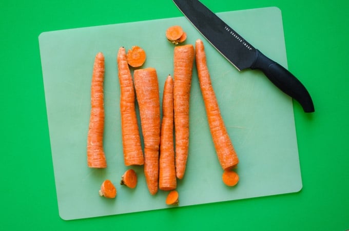 Carrots on a cutting board with green background