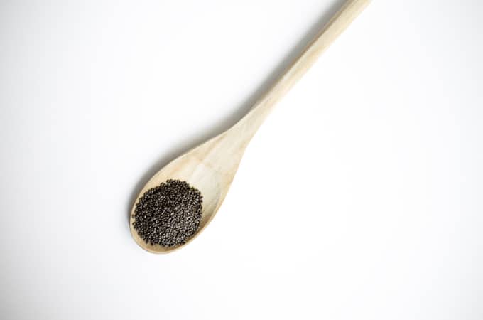 Photo of chia seeds on a wooden spoon with a white background