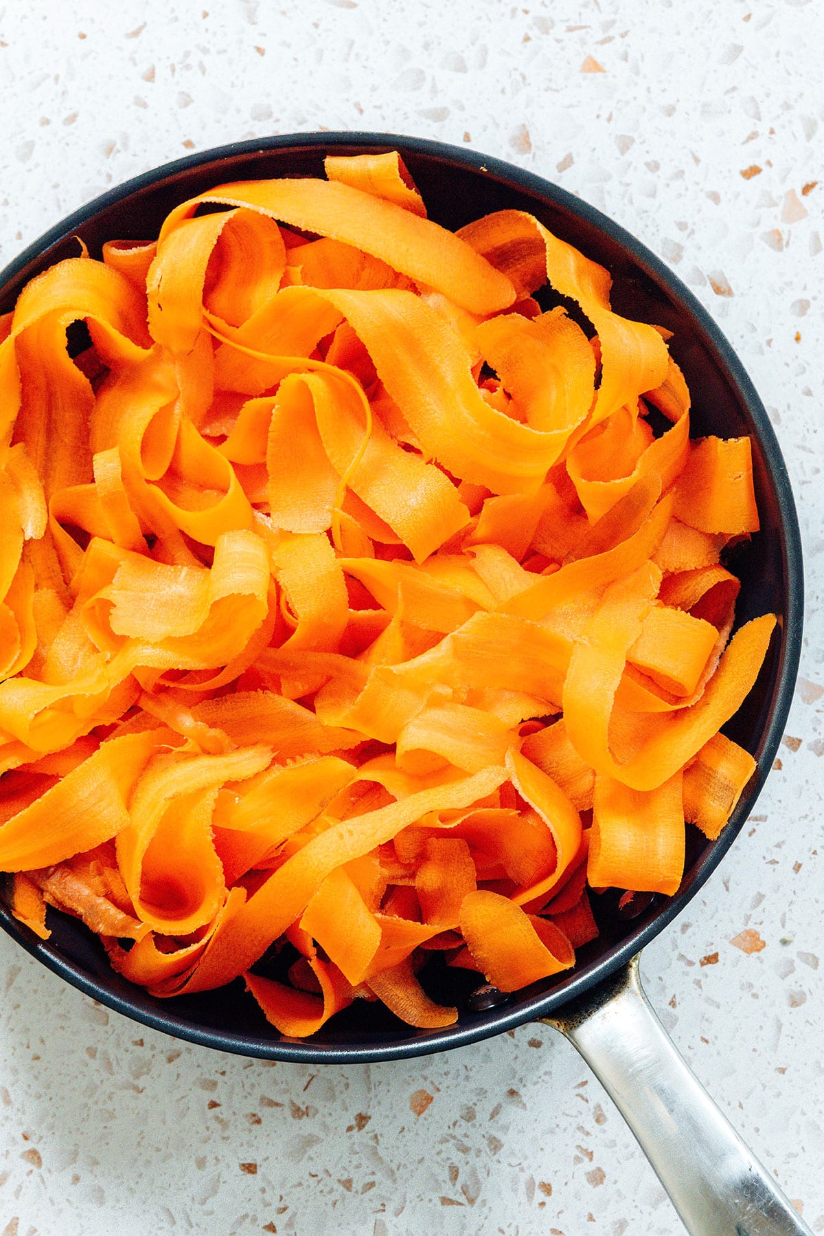 Shaved carrot noodles in a saute pan.