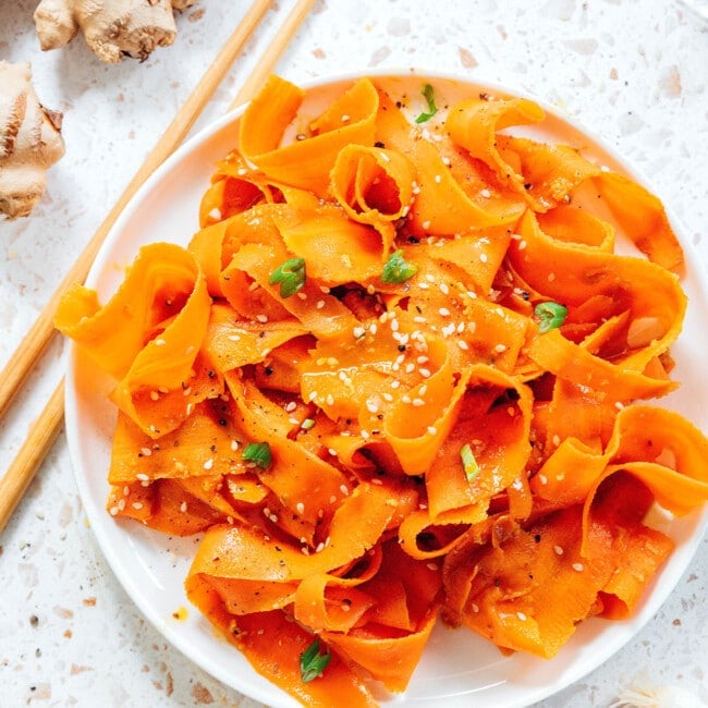 Carrot noodles on a plate with chopsticks.