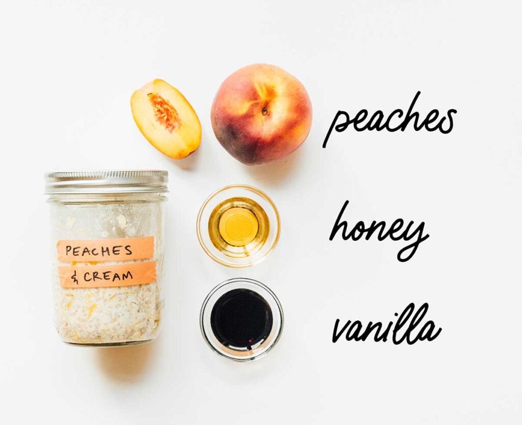 A jar of peaches and cream overnight oats laid out next to peaches, honey, and vanilla