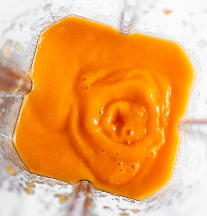 Tropical carrot juice in a blender on a white background
