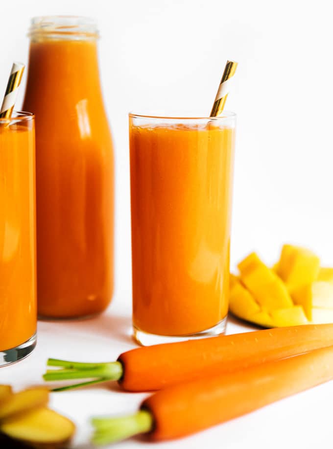 Tropical carrot juice recipe in three glasses on a white background