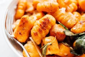 Closeup photo of sweet potato gnocchi in a bowl on a white background