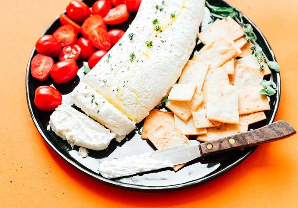 Greek yogurt cheese on a plate with crackers and tomatoes