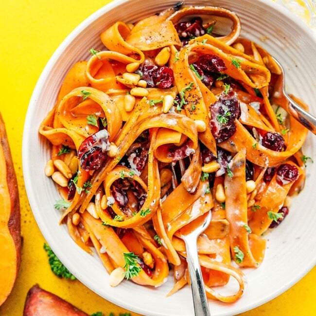 Sweet potato fettuccine noodles in a bowl on a yellow background