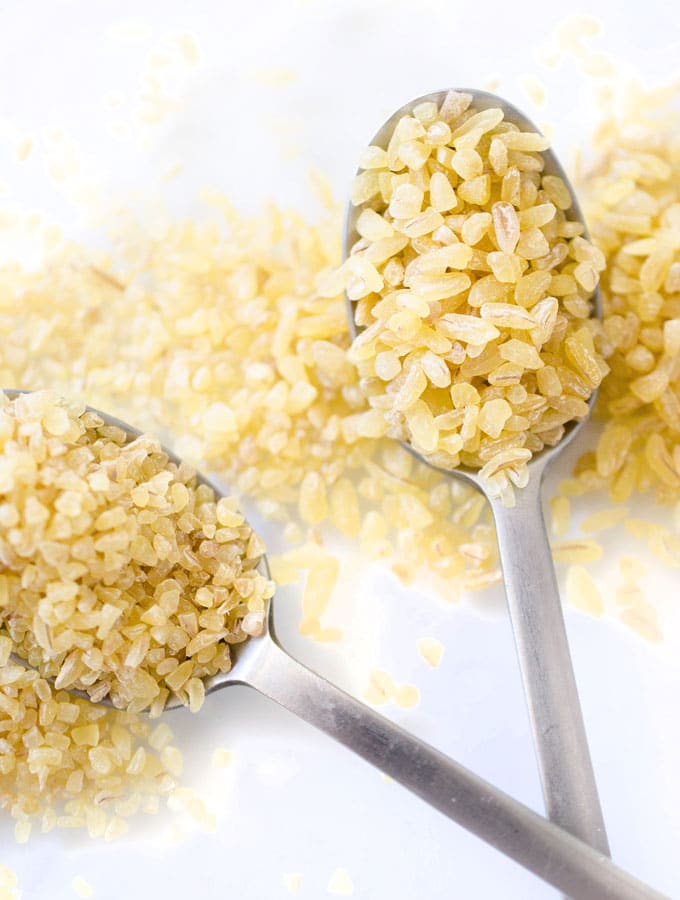Closeup photo of bulgur grains and a spoon - Everything you need to know about cooking with bulgur, an ancient whole wheat grain that's packed with protein, fiber, and vitamins!