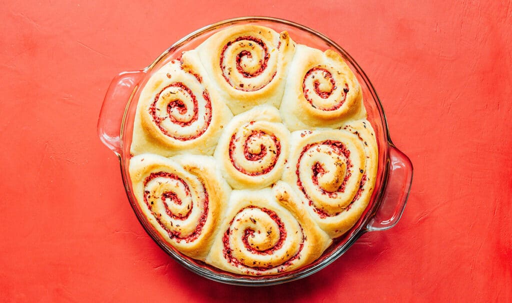 A glass baking dish filled with seven cranberry orange cinnamon rolls