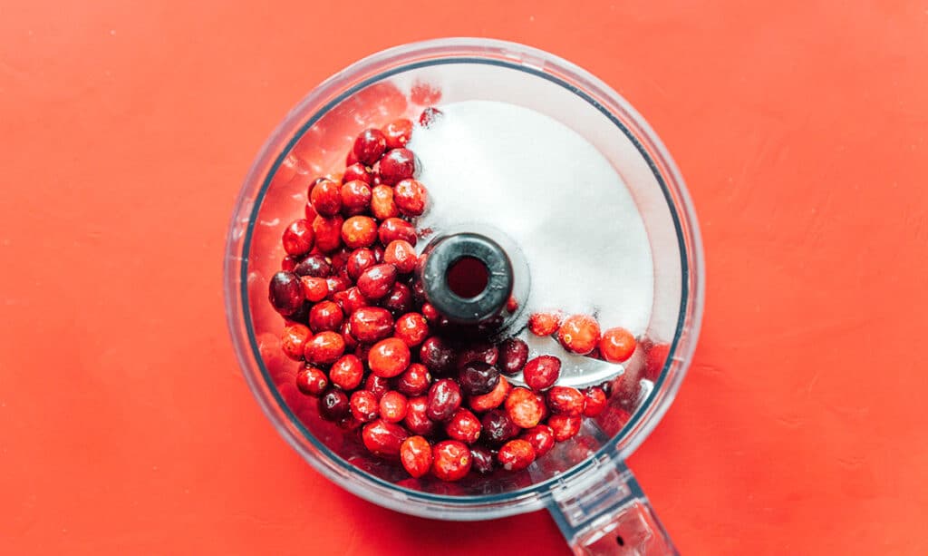 A food processor filled with unmixed cranberry filling ingredients