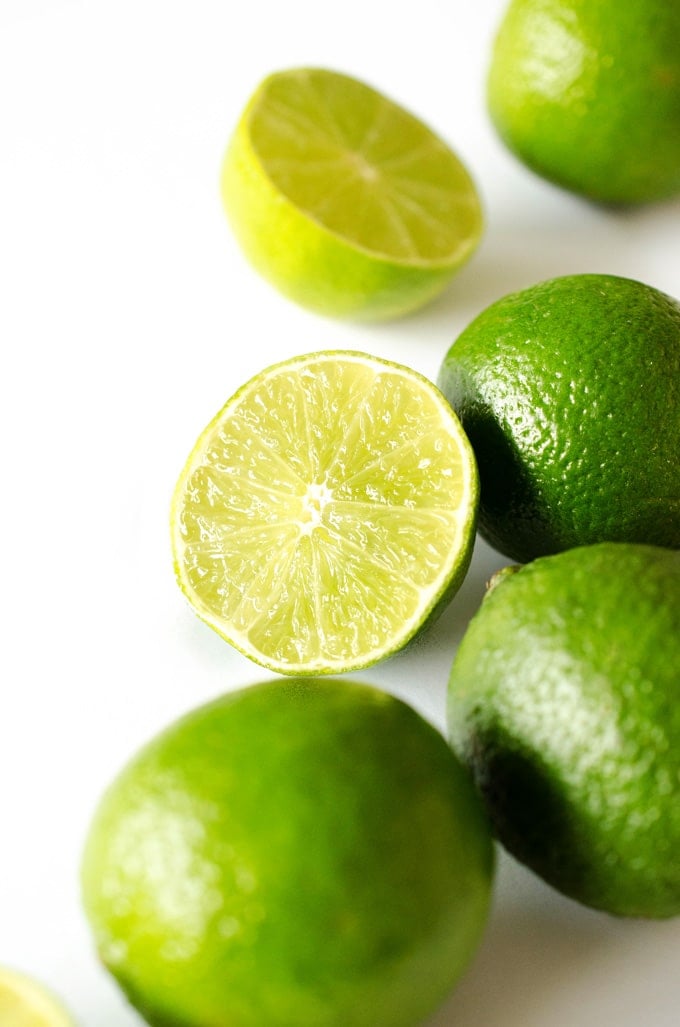 Close up photo of limes cut in half on a white background