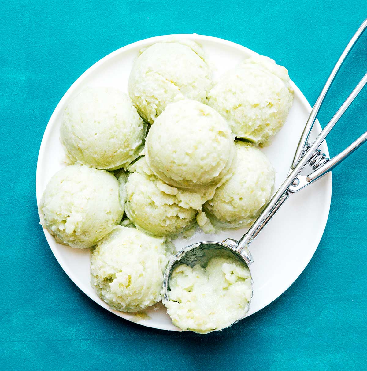 Scoops of green grape sorbet on a white plate on a blue background