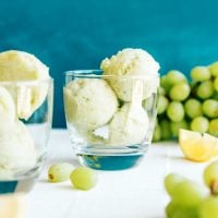 Scoops of green grape sorbet into a glass on a blue background