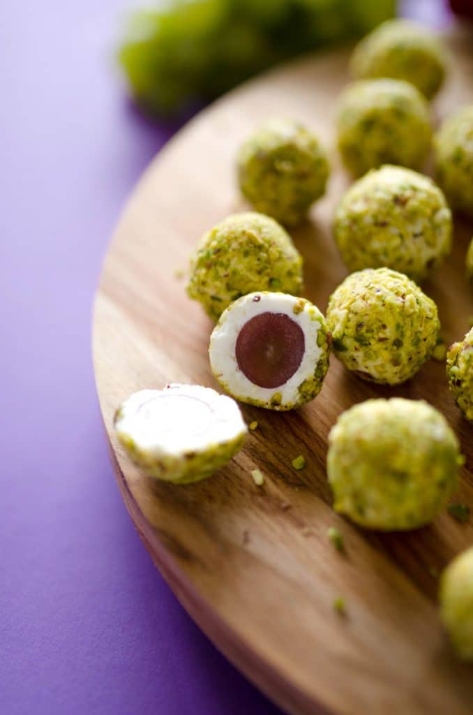 Grape goat cheese bite cut in half - These goat cheese covered grapes rolled in pistachios are crunchy on the outside, creamy on the inside, and bursting with juicy flavor!