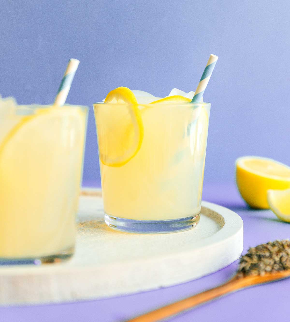A glass of lavender lemonade topped with lemon slices