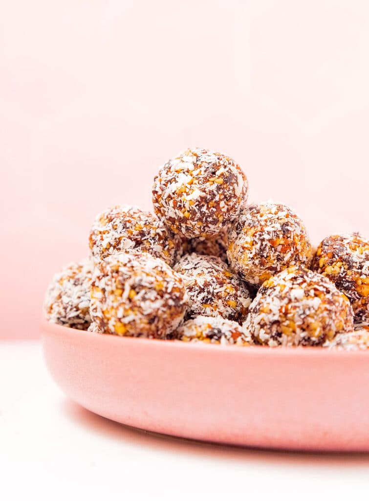 A pink bowl filled with coconut coated no bake energy bites