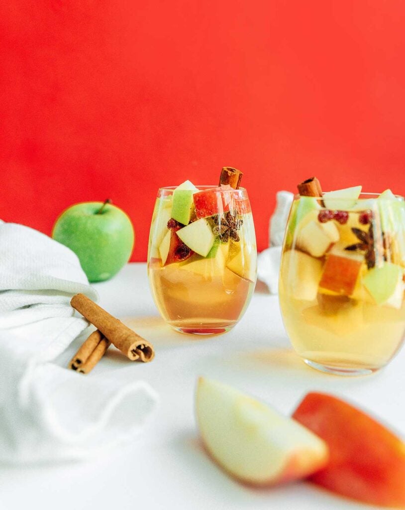 A wine glass filled with autumn apple sangria complete with apple pieces and cinnamon