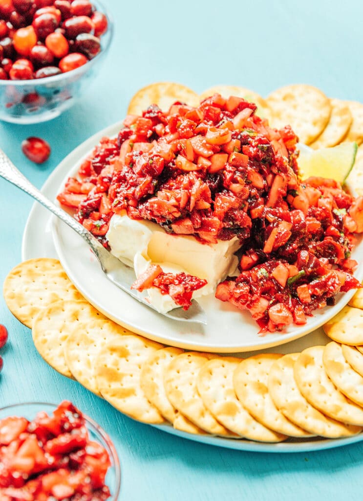 A platter of savory roasted cranberry salsa surrounded by an arrangement of crackers