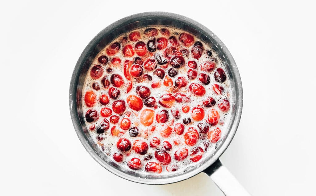 A pot filled with simmering cranberry sauce ingredients 